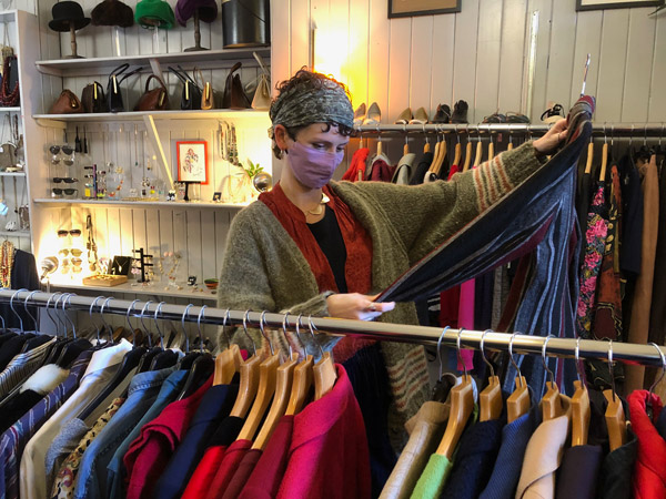 Vintage Shopping Tour in Edinburgh and Scotland woman searching through clothing rail in a charity shop in Edinburgh